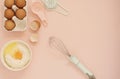 Ingredients and kitchen bake tools for cooking cake or sweets - eggs, flour, whisk on a pastel punchy pink background. Top view of