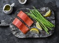 Ingredients for lunch - fresh raw organic salmon, green asparagus on a cutting board on a dark background, top view