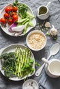 Ingredients for lunch - orzo pasta, asparagus, green peas, broccoli, cherry tomatoes, olive oil, cream and spices. On a gray backg Royalty Free Stock Photo
