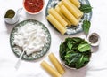 Ingredients for making cannelloni with spinach and ricotta baked with tomato sauce and mozzarella on a light background, top view Royalty Free Stock Photo