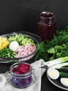 Ingredients for making cold borsch. Plate with boiled eggs and green herbs. Jars with beetroot juice and beetroot slices. Black Royalty Free Stock Photo