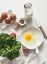 Ingredients for making an omelet - eggs, milk, pepper, spinach on a light background, top view