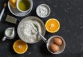 Ingredients for making orange cake with olive oil - flour, eggs, olive oil, powdered sugar on a dark background Royalty Free Stock Photo