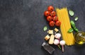 Ingredients for making pasta. Raw spaghetti with tomato and basil on a black background. View from above Royalty Free Stock Photo