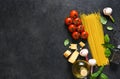 Ingredients for making pasta. Raw spaghetti with tomato and basil on a black background. View from above Royalty Free Stock Photo