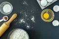 Flour, baking powder, cinnamon, eggs and rolling pin for rolling dough on a black background