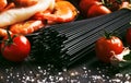 Ingredients for the preparation black pasta with seafood, tomatoes and white dry wine, black food cooking background, still life, Royalty Free Stock Photo