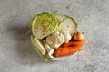 Ingredients for preparing a vegetable broth or soup on a plate - Savoy cabbage, carrots, celery root, onion, cauliflower, leek,