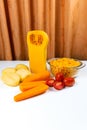 Ingredients for pumpkin soup. Diced pumpkin, carrots, potatoes, tomatoes and half a peeled pumpkin on on white table on orange Royalty Free Stock Photo