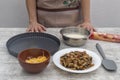 Ingredients for quiche of cheese, mushrooms and bacon on work table on background body and woman hands with blur. Concept of home