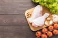 Ingredients and raw chicken leg on cutting board on wooden background