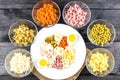 Ingredients shredded for salad in transparent plates on a black wooden background. Olives, pickled cucumbers, sausages, carrots, p Royalty Free Stock Photo