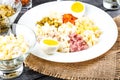 Ingredients shredded for salad in transparent plates on a black wooden background. Olives, pickled cucumbers, sausages, carrots, p Royalty Free Stock Photo