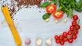 Ingredients for tasty pasta: raw cherry tomatoes, basil, garlic, pepper on the gray concrete kitchen table. Cooking concept Royalty Free Stock Photo