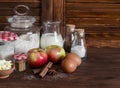 Ingredients and tools for baking - flour, eggs, butter, apples, cinnamon on a brown rustic wooden surface. Royalty Free Stock Photo