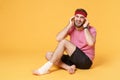 Ingured crying bearded fitness guy sportsman in headband t-shirt in home gym isolated on yellow background. Workout