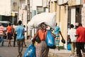 Inhambane, Mozambique, September, 19th 2018: African woman carrying large packages on a street full of men