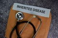 Inherited Disease text with document brown envelope and stethoscope isolated on office desk