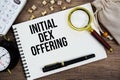 Initial DEX Offering text written on notepad with pen, alarm clock, magnifying glass and calculator on wooden background Royalty Free Stock Photo