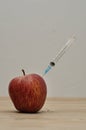 An injection needle stuck into an apple