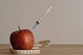 An injection needle stuck into an apple with a measuring tape