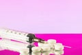injection syringe with needle and white pills on pink background Royalty Free Stock Photo