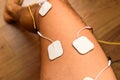 An injured athlete applies ems electrodes to his legs to recover muscle tone with a tensile electrostimulation system