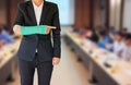 Injured businesswoman with green cast on hand and arm on blurred