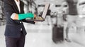 Injured businesswoman with green cast on hand and arm on traveler in motion blur in airport interior background, ,body injury con