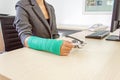 Injured businesswoman with green cast on the wrist holding white Royalty Free Stock Photo
