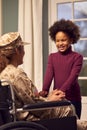 Injured Female American Soldier Wearing Uniform Sitting In Wheelchair Holds Hands With Daughter