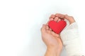 Injured hands holding a red heart in white background. Sacrificial and selfless love and genuine kindness concept. Royalty Free Stock Photo