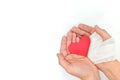 Injured hands holding a red heart in white background. Sacrificial and selfless love and genuine kindness concept. Royalty Free Stock Photo