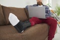 Injured man with broken leg work on laptop at home