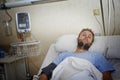 Injured man lying in bed hospital room resting from pain looking in bad health condition