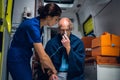 Injured Man sitting with an oxygen mask in an ambulance car, a young nurse is holding his hand Royalty Free Stock Photo