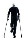Injured man walking rear view with crutches silhouette