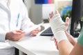 Injured patient showing doctor broken wrist and arm with bandage Royalty Free Stock Photo