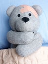 Injured Teddy Bear plasters bed hugging