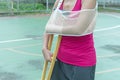 Injured woman broken arm and leg holding crutch Royalty Free Stock Photo