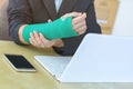 injured woman with broken hand sitting and holding green cast wo