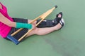 Injured woman wearing sportswear painful arm with gauze bandage, arm cast and wooden crutches sitting on floor