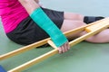 Injured woman wearing sportswear painful arm with gauze bandage, arm cast and wooden crutches sitting on floor Royalty Free Stock Photo