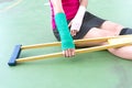 Injured woman wearing sportswear painful arm with gauze bandage, arm cast and wooden crutches sitting on floor