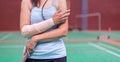 injured woman wearing sportswear painful arm and leg with gauze bandage, arm cast holding badminton racket standing on badminton Royalty Free Stock Photo