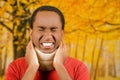 Injured young positive black hispanic male wearing neck brace, holding hands in pain around support making faces of Royalty Free Stock Photo