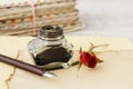 Inkwell, pen and dried roses on vintage paper background. Love letters idea Royalty Free Stock Photo