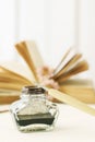 Inkwell and vintage pen. Open book in the background Royalty Free Stock Photo