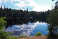 Inland lake of glacial origin on sunny day. Reflection of forest and clouds in the water. Karelian nature in the summer.