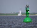 Inland shipping regulation Green light buoy with solar panels as energy source , Blurred, background with sailboat